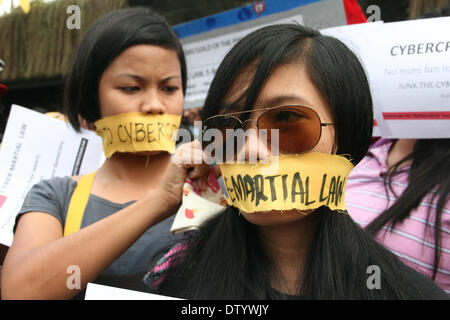 Manila, Philippine, . 25th Feb, 2014. A protester tying a yellow ribbon, which symbolizes the Aquino administration and the Cybercrime Law, to cover another protesters' lips during the Black Tuesday demonstration at the Edsa Shrine in Quezon City. -- Different media groups, together with student activists, commemorated the 28th anniversary of the Edsa Revolution with a protest rally against the Cybercrime Law. Credit:  J Gerard Seguia/NurPhoto/ZUMAPRESS.com/Alamy Live News Stock Photo