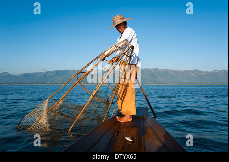 A Local Man In Catches Fish In The Ocean On A Sunny Day To Cook It For  Lunch. Indonesian Man In Red Hoodie Catches Fish On A Fishing Rod. A  Fisherman On