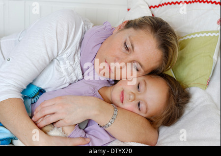 Mother and daughter cuddling in bed, hugging Stock Photo