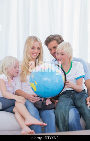 Happy family looking at globe on couch Stock Photo