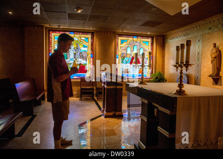A uniformed student at a private Catholic high school in San Juan Capistrano, CA, prays in the school's chapel. Stock Photo