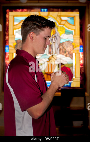 A uniformed student at a private Catholic high school in San Juan Capistrano, CA, prays in the school's chapel. Stock Photo