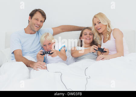 Family playing video games in bed Stock Photo