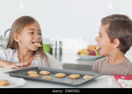 Siblings with cookies in their mouth Stock Photo