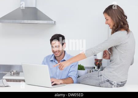 Wife pointing at the laptop of her husband Stock Photo