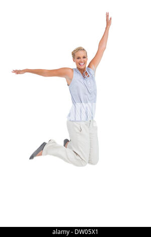 Blonde woman jumping with hands up in air Stock Photo