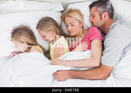 Parents sleeping in bed with their twins Stock Photo