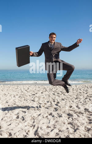 Cheerful businessman jumping on the beach Stock Photo