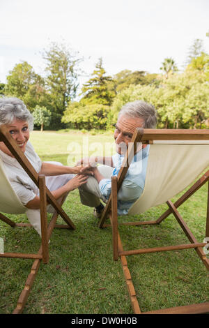 Smiling mature couple lying on sun loungers Stock Photo