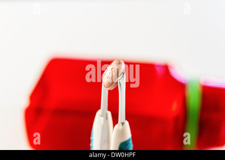 A Lisinopril tablet being held by tweezers Stock Photo