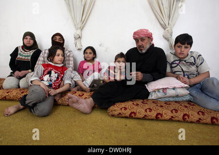 Feb. 21, 2014 - Al-Kitteh, Jarash, Jordan - Ahmad Mansour, 54, with his family pose for a picture at his house in the village of al-Kitteh western city of Jerash, 50 km northern the Jordanian capital Amman on February 21, 2014 . Mansour arrived on foot on a stretcher as a Syrian refugee to Jordan one year ago after he was wounded in his left hand and his back by a mortar shell landed on his house in Daraa, followed by his wife and his twelve children after three months (Credit Image: © Ahmad Abdo/APA Images/ZUMAPRESS.com) Stock Photo