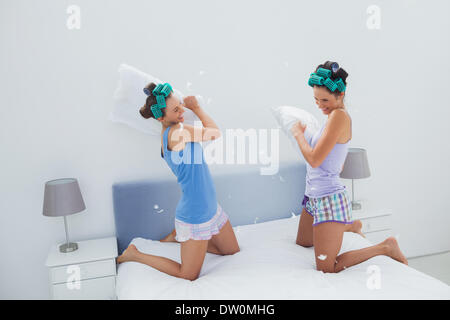 Girls in hair rollers having pillow fight Stock Photo