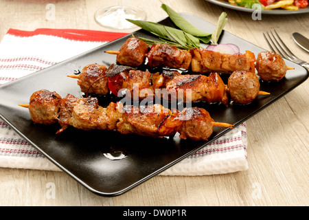 skewers of meat cooked on a plate Stock Photo