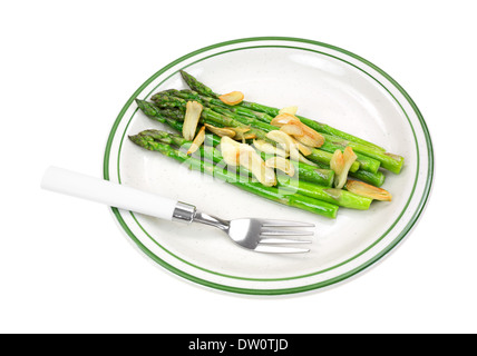 A serving of cooked asparagus with garlic on a plate with fork. Stock Photo