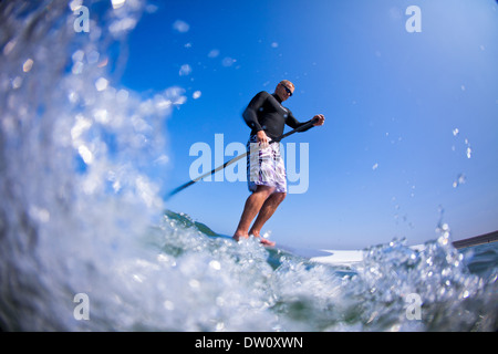 Stand up paddleboarder paddles in North Devon's clear Atlantic waters in summer. Stock Photo