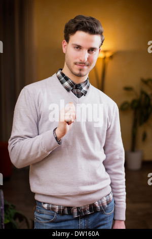 Handsome young man pointing finger at himself, smiling. Indoors shot inside a house Stock Photo