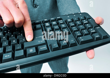man wearing a suit pressing the enter key of a computer keyboard Stock Photo