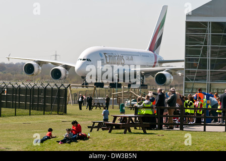 Emirates Airbus A380 taxiing past Concorde hanger at Manchester Airport with school children watching on.