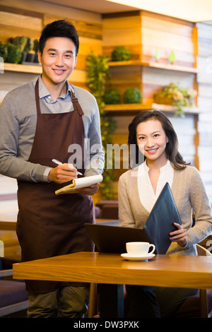 Waiter taking order from woman at restaurant Stock Photo