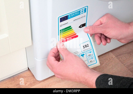 Man Sticking an Energy Rating Performance Sticker to a Washing Machine, UK MODEL RELEASED Stock Photo