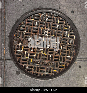 Various cigarette butts set in the grooves of an NYC sewer lid on 6th Avenue in Manhattan. Stock Photo