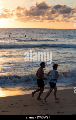 Manly North Steyne Beach at dawn sunrise with middle aged 50s couple running along shoreline Sydney New South Wales Australia Stock Photo