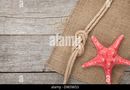 Starfish with ship rope and burlap on wooden background with copy space Stock Photo