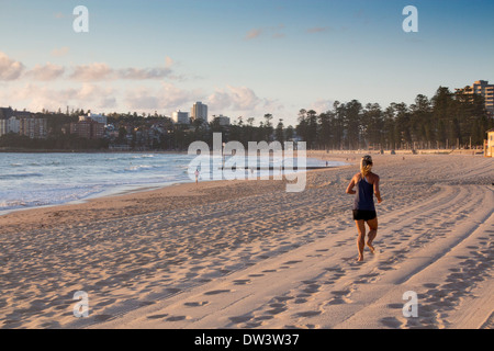 Manly North Steyne Beach at dawn with female runner jogger running along sand Sydney New South Wales NSW Australia Stock Photo