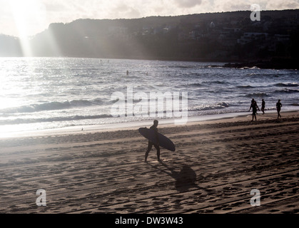 Surfer walking along North Steyne beach Manly Northern Beaches Sydney New South Wales NSW Australia Stock Photo