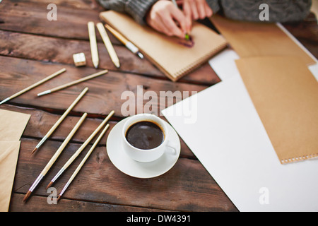 Image of cup of coffee and objects for hand drawing on background of male hands over notepad Stock Photo