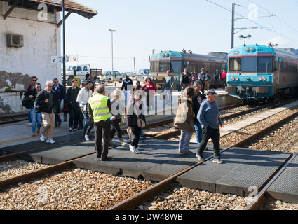 Passengers crossing the railway line under supervision, Faro rail station Algarve, Portugal, Europe Stock Photo