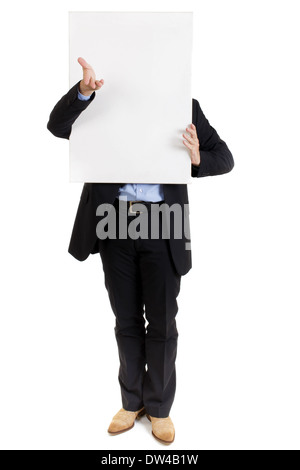 Businessman in a smart suit standing with a blank white sign held in front of his face gesturing with his hand Stock Photo