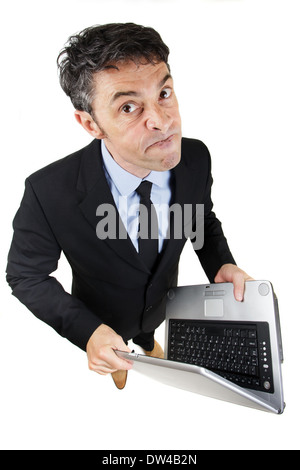Pugnacious businessman holding a laptop computer in his hands standing looking up at the camera Stock Photo