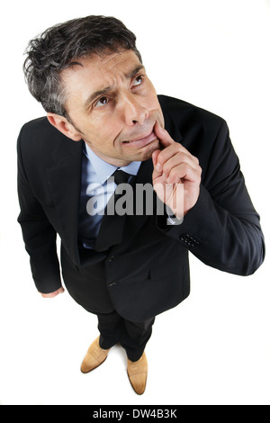 high angle full length portrait of a thoughtful frowning businessman standing looking up with his finger to his mouth