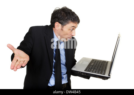 Businessman shrugging his shoulders and gesturing in disbelief or indifference as he reads his handheld laptop Stock Photo