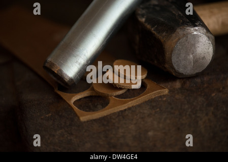 Leather with a hammer and punch used to make circular pieces for a tool and knife handles. Stock Photo
