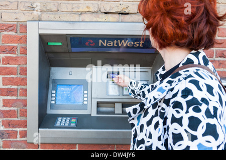 Woman using an ATM cash machine at a NatWest bank, Nottinghamshire, England, UK Stock Photo
