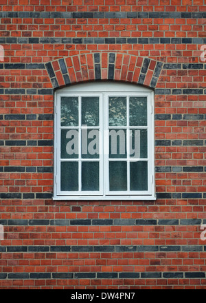 White painted wood arched window in a red brick wall Stock Photo