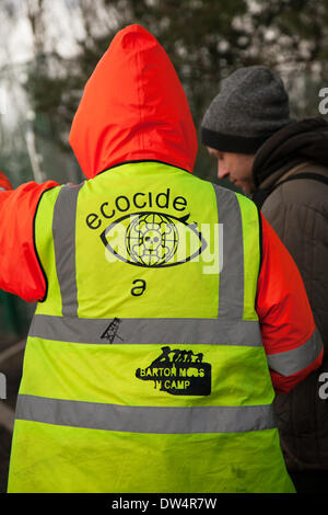 Manchester, Barton Moss Camp, UK. 27th February, 2014.  Protester wearing ECOCIDE hi-vis jacket as protests continue at IGAS Drilling Site.  Greater Manchester Policing operation at Barton Moss Drilling Site as protesters seek to delay and obstruct delivery vehicles and drilling equipment en-route to the controversial gas exploration site. Fracking protestors have set up a camp at Barton Moss Road, Eccles a potential methane-gas extraction site in Salford, Greater Manchester. Credit:  Mar Photographics/Alamy Live News. Stock Photo
