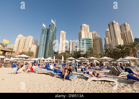 Dubai holiday; Crowds of tourists on holiday sunbathing on Jumeirah Beach in winter, Hilton Hotel , Dubai, UAE, United Arab Emirates, Middle east Stock Photo