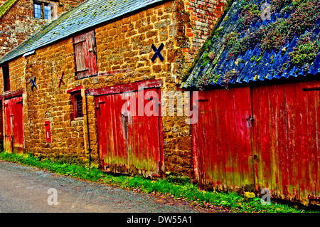 Stone buildings and barn with faded red paint on doors. Stock Photo