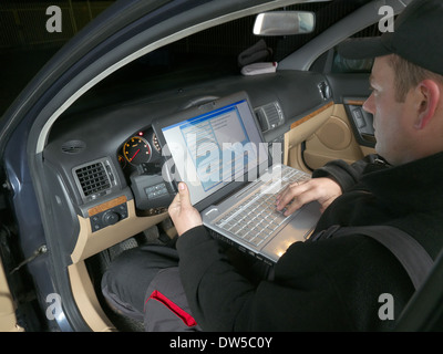 Auto mechanic checking vehicle identification number of the car using laptop hooked up to the car onboard computer Stock Photo
