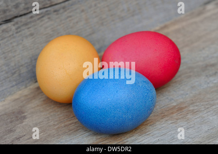 three painted eggs in straw on wooden board Stock Photo