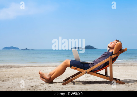 happy business man with laptop relaxing on the beach Stock Photo