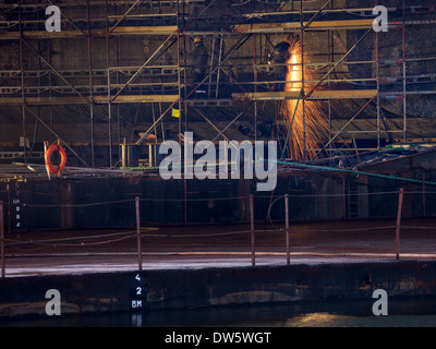 A shipyard steel worker burning steel on scaffolding. Stock Photo