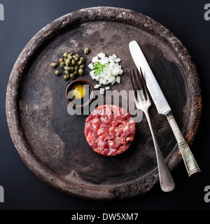 Steak Tartare with capers and fresh onions on black textured background Stock Photo