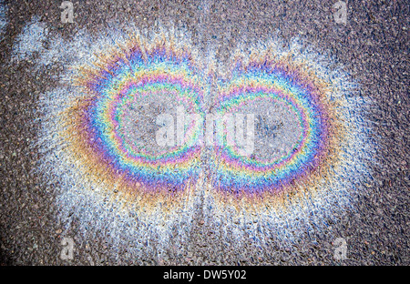 Oil spots on wet Tarmac road forming rainbow interference patterns Stock Photo