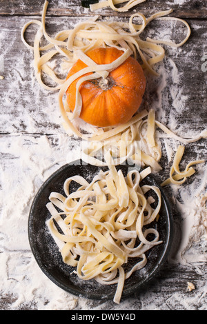 Top view on raw homemade pasta with pumpkin and flour over old wooden table Stock Photo