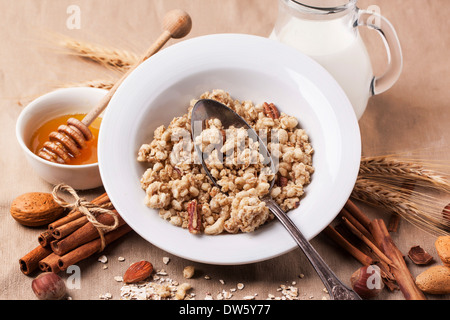 Plate of muesli with milk, honey, cinnamon and nuts over textile background. See series Stock Photo