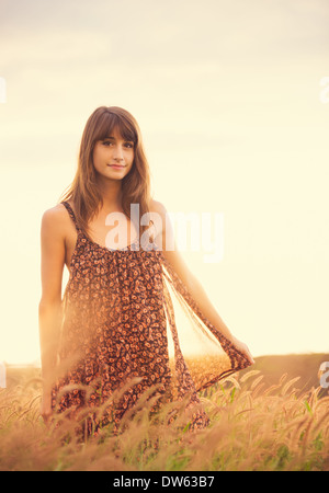 Beautiful woman in golden field at sunset, Fashion lifestyle, Vibrant color, Backlit warm tones Stock Photo